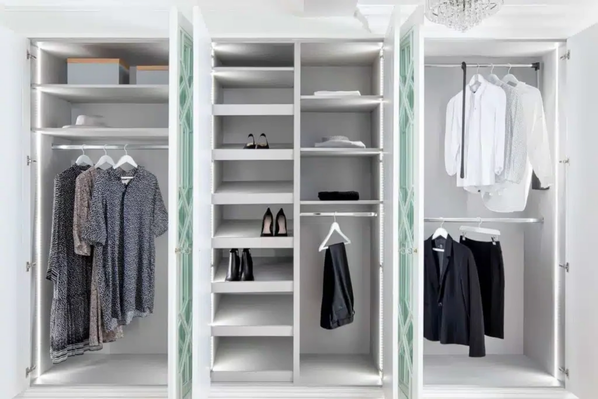 White wardrobes in a brightly lit room with a few clothes hanging and a few pairs of shoes. 