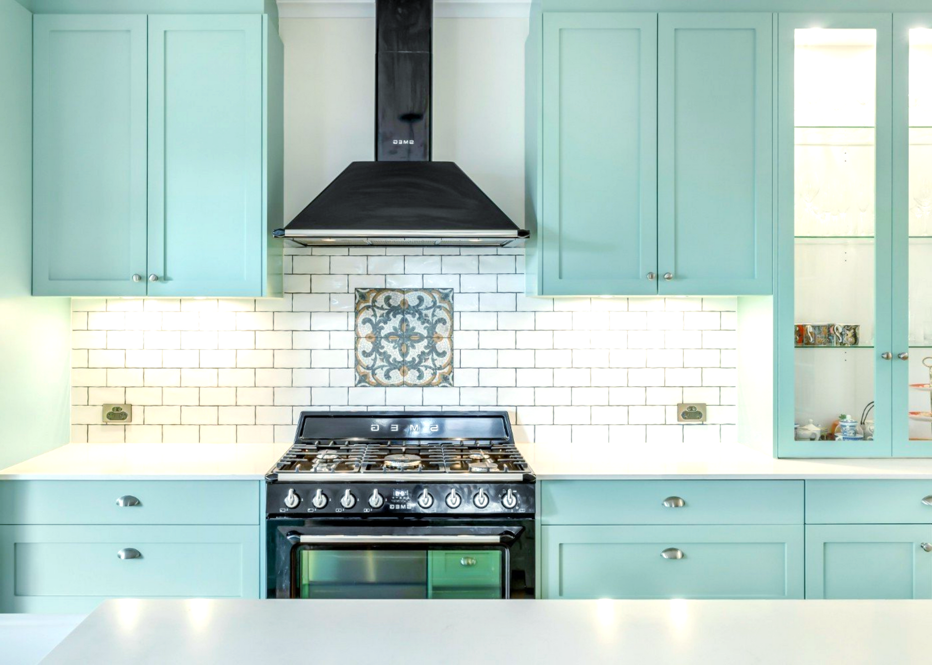 A kitchen with contemporary cabinets, white splashbacks and black oven and rangehood.