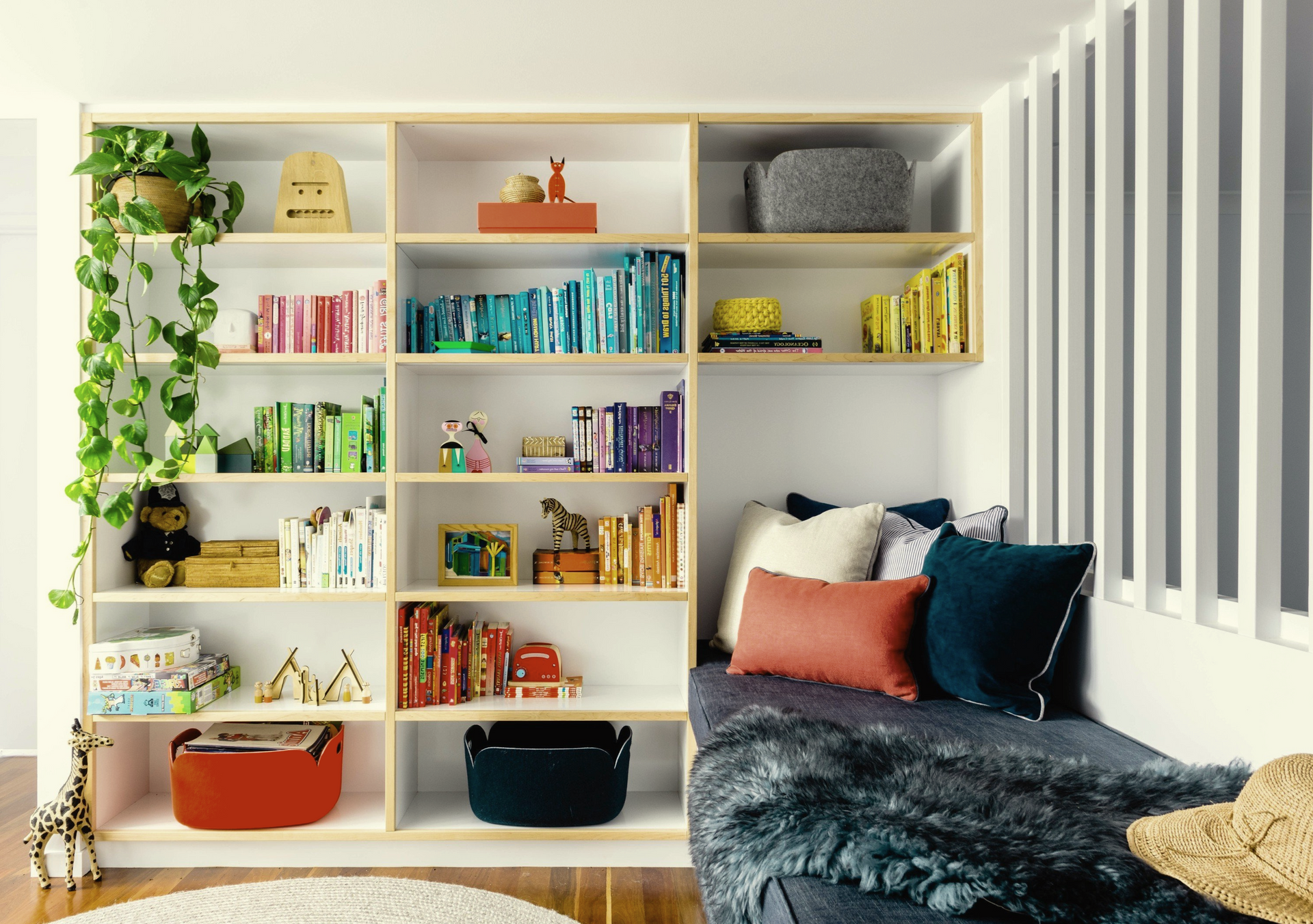A living room with a couch and shelves filled with books and toys.