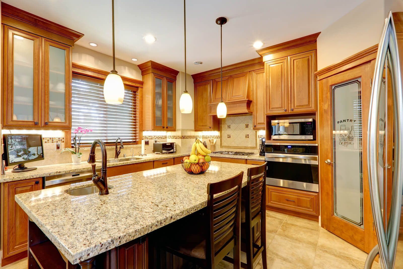 A kitchen with granite counter tops , wooden cabinets , stainless steel appliances and a large island.