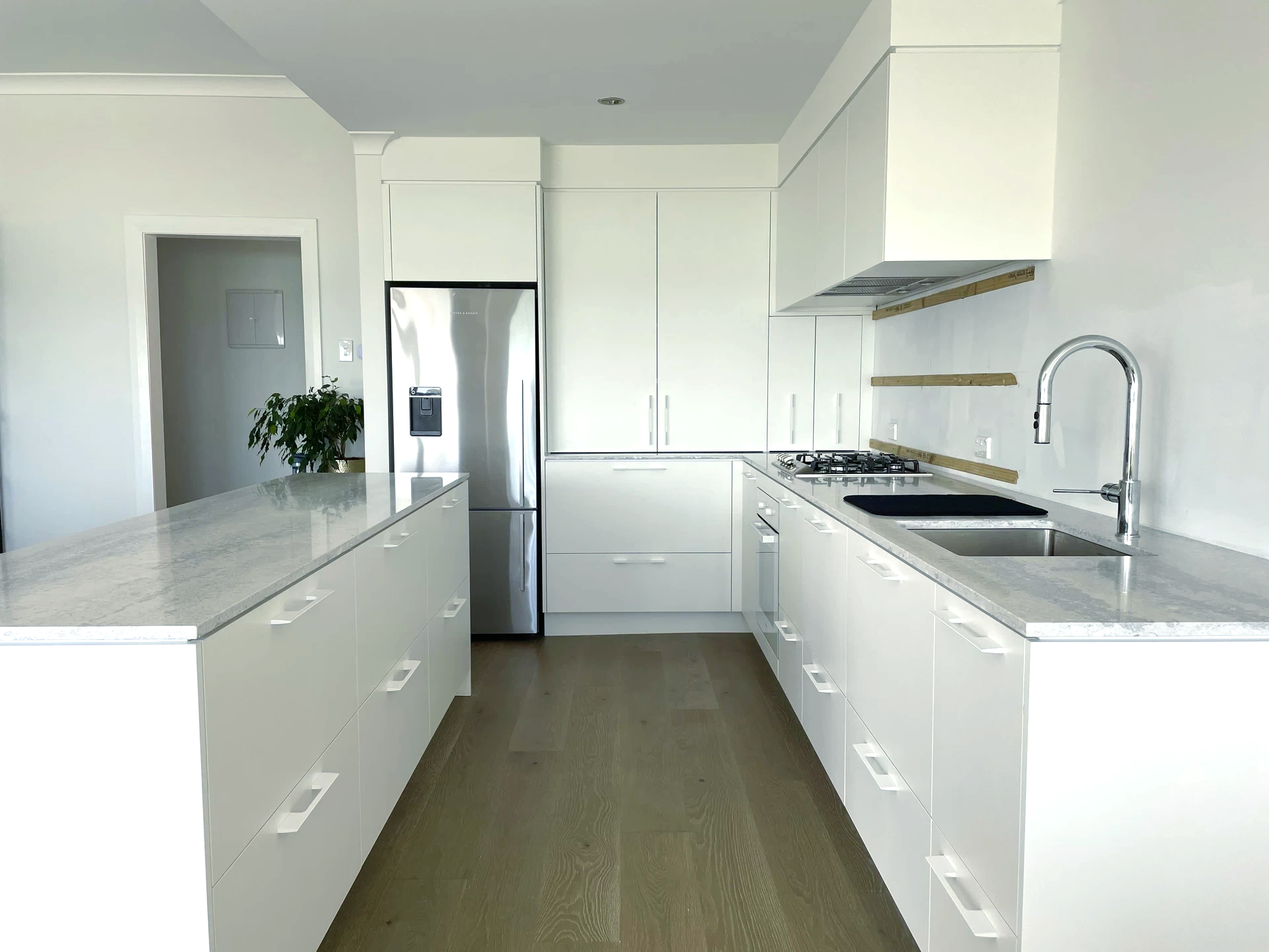 A kitchen with white cabinets, stainless steel appliances, a sink, and a refrigerator.