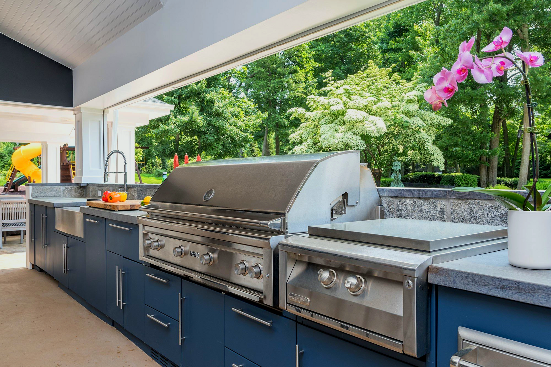 A kitchen with blue cabinets and a stainless steel grill.