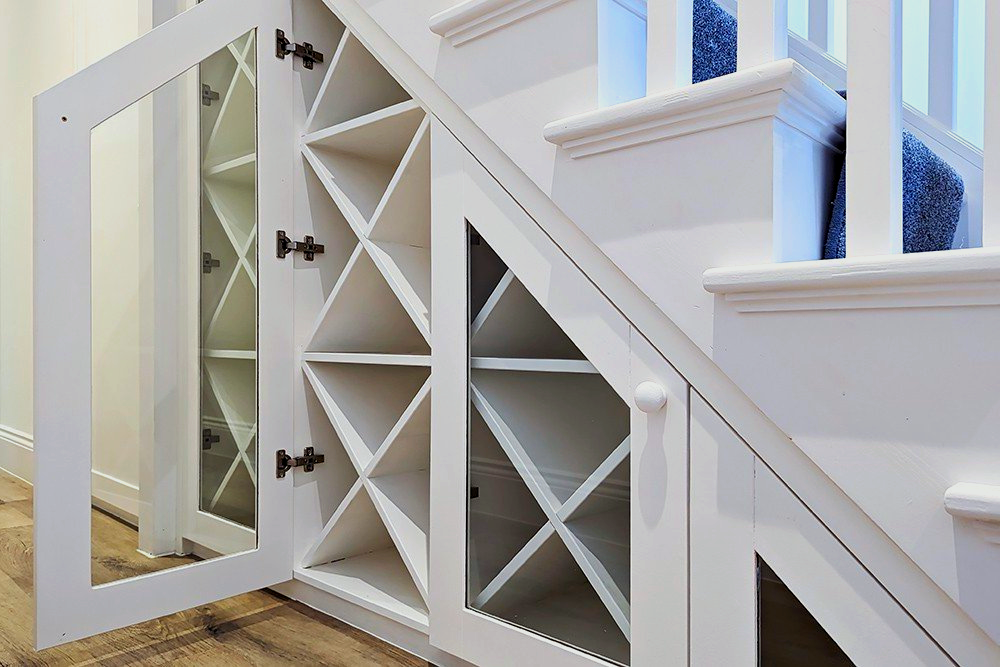 There is a wine rack under the stairs with the door open.