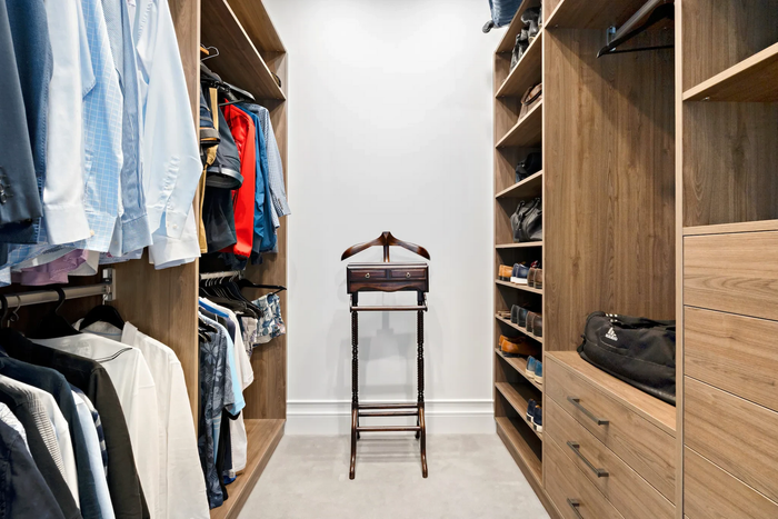 A walk in closet filled with clothes and a valet stand.