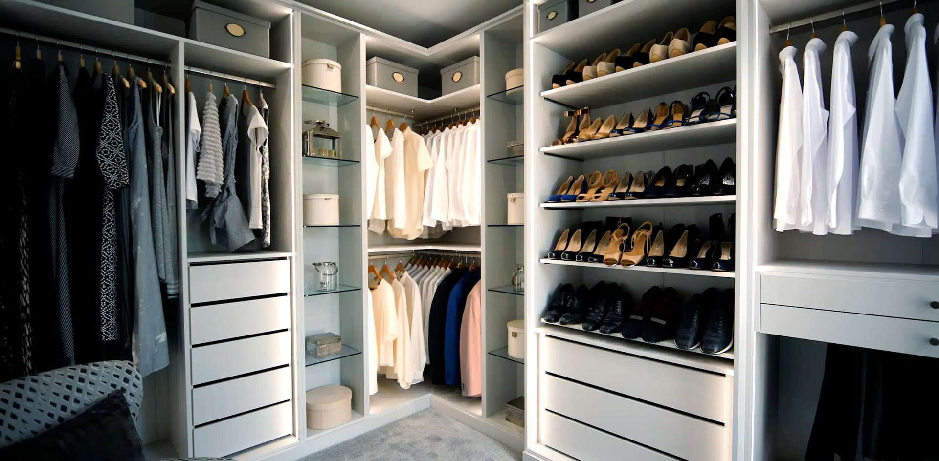 A walk in closet filled with lots of clothes and shoes.