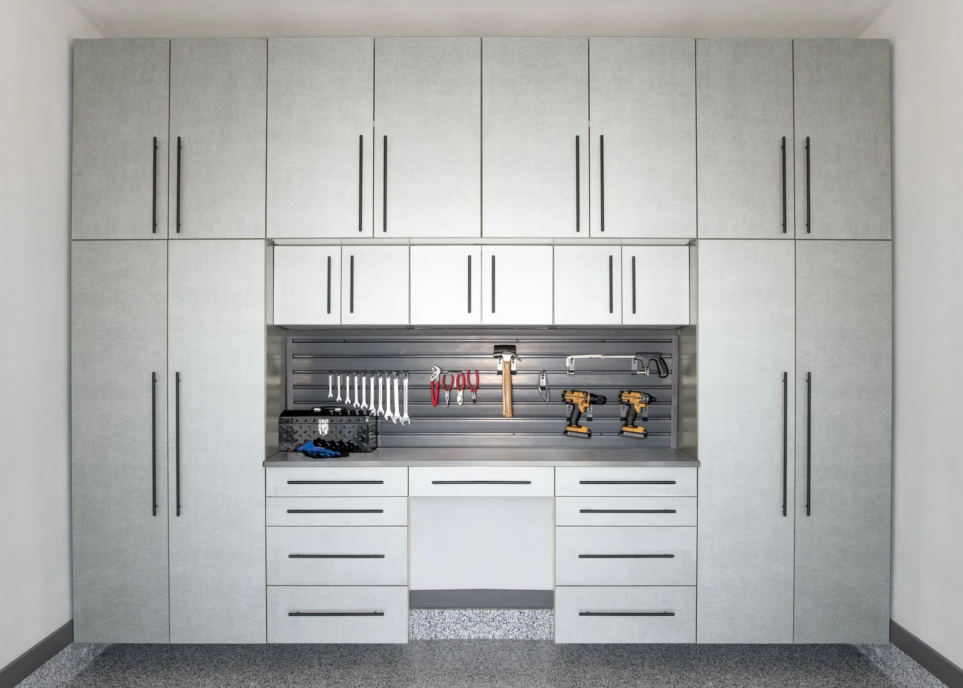 A garage with lots of cabinets and drawers and a workbench.