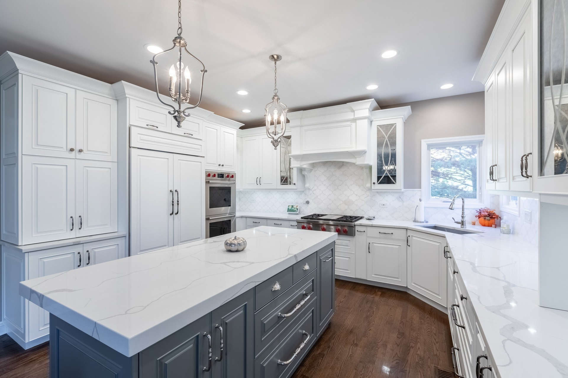 A kitchen with white cabinets and a large island in the middle.