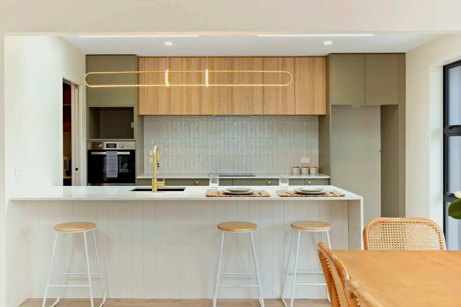 A kitchen with a table, chairs, stools and a sink.