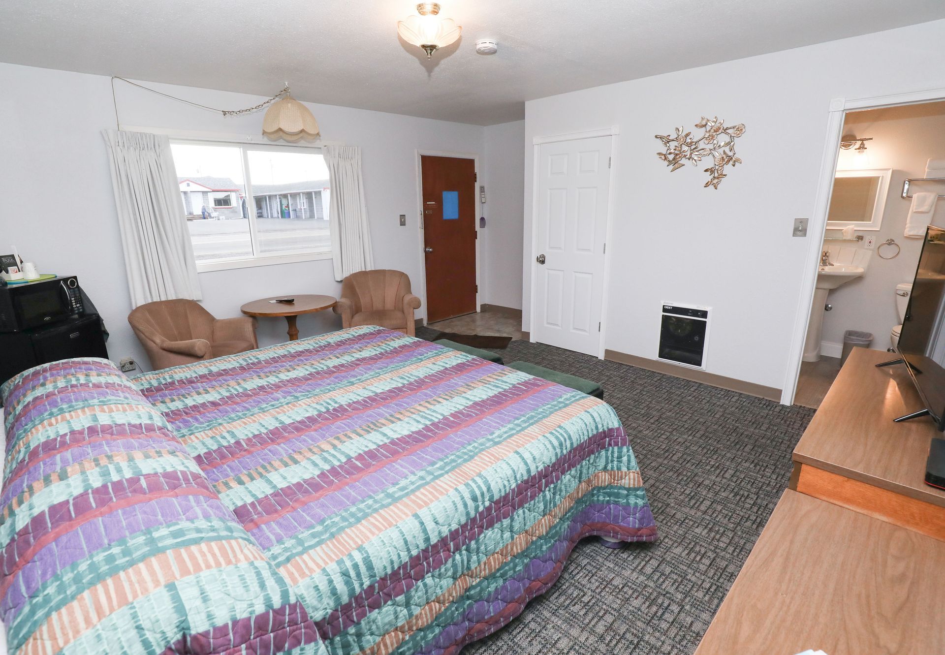 A hotel room with a king size bed and chairs