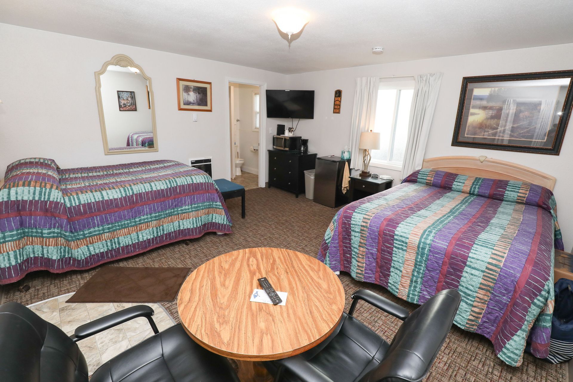 A hotel room with two beds , a table and chairs.