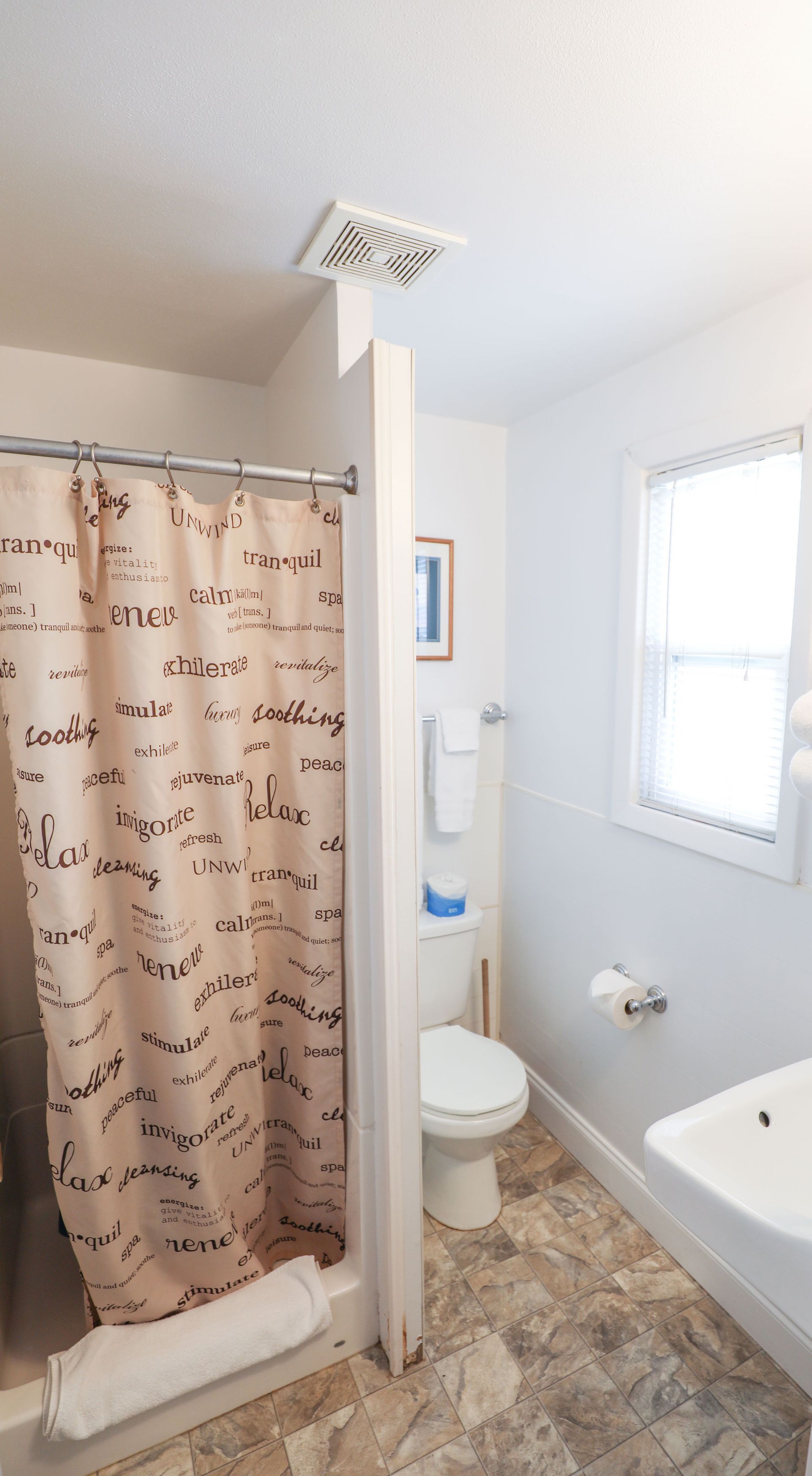 A bathroom with a shower , toilet , sink and window