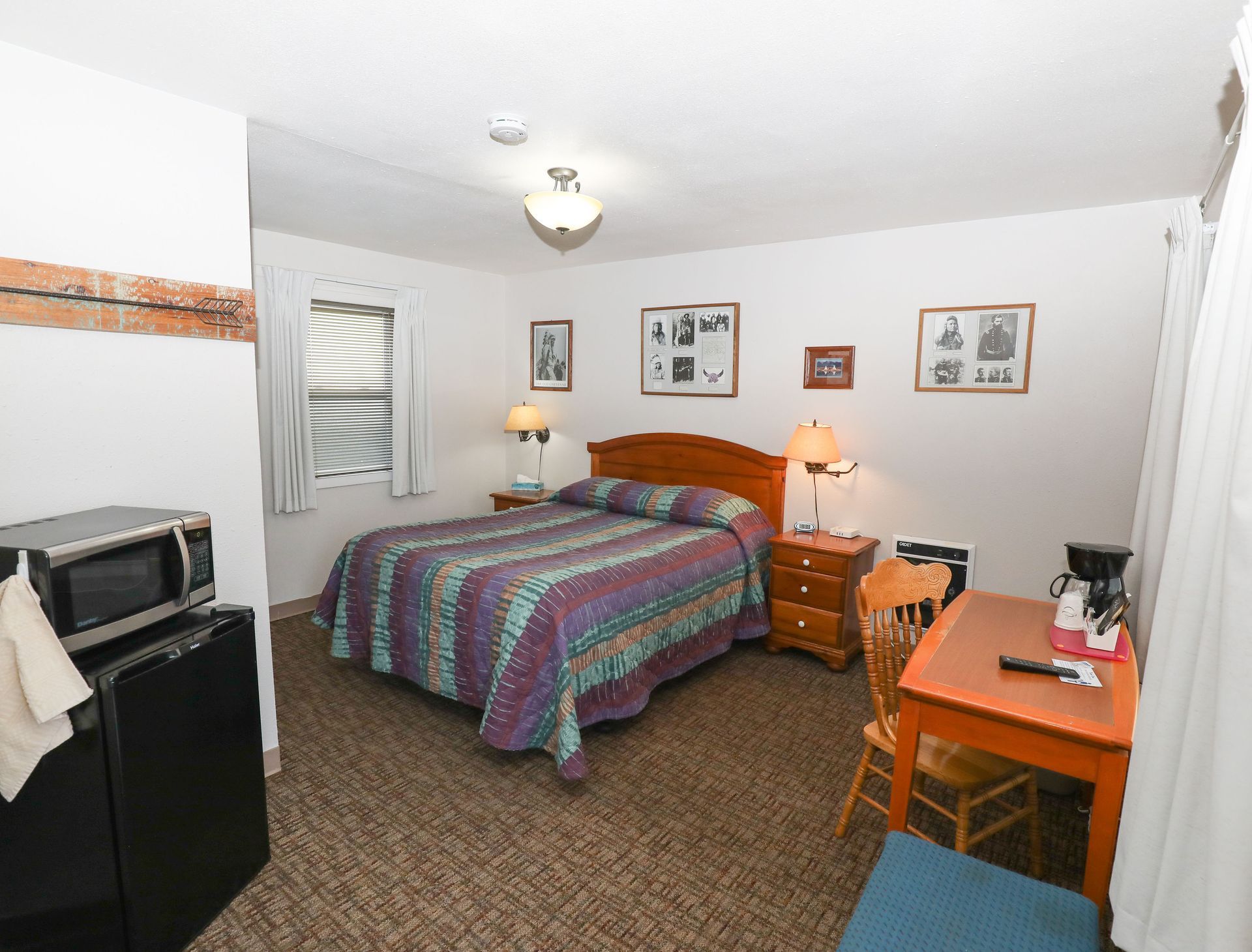 A hotel room with a bed , table , chairs and microwave.