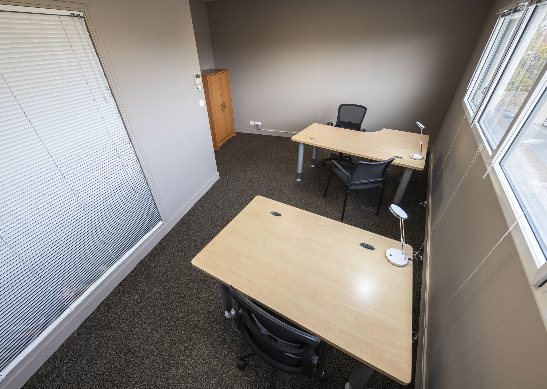 Bureau avec trois bureaux, des chaises, une fenêtre et une porte.