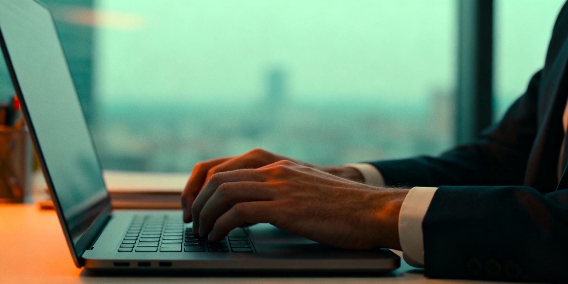 Person in blue shirt holding a gold credit card and tablet near a laptop and calculator.