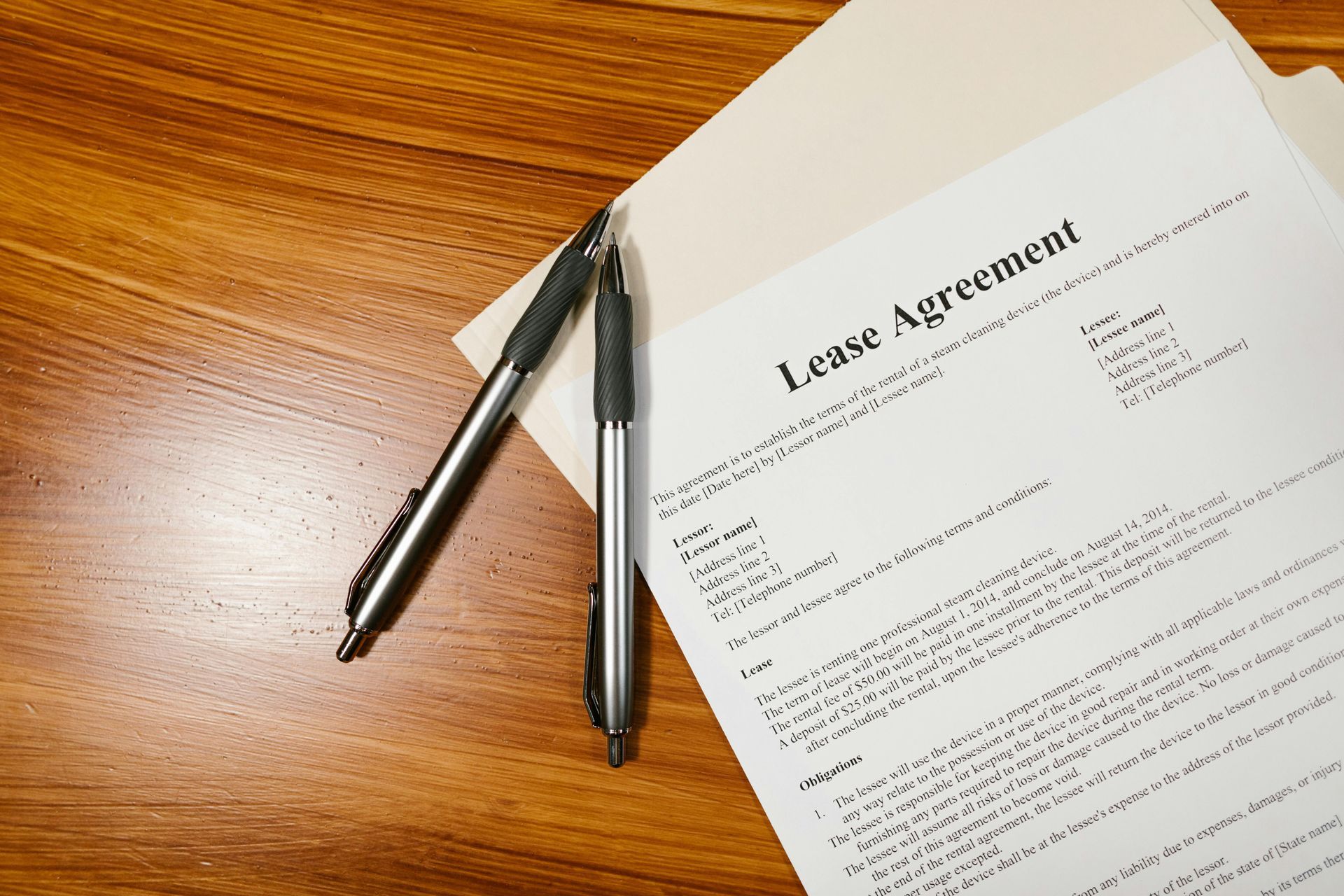 Pens resting on a signed lease agreement on a wooden desk