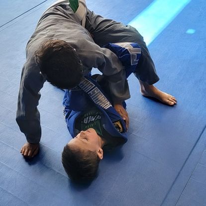 two young boys are practicing jiu jitsu on a blue mat .
