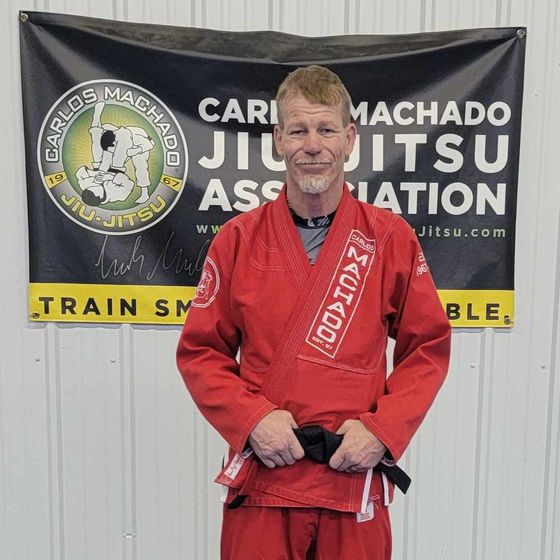 a man in a black karate uniform is standing on a basketball court .