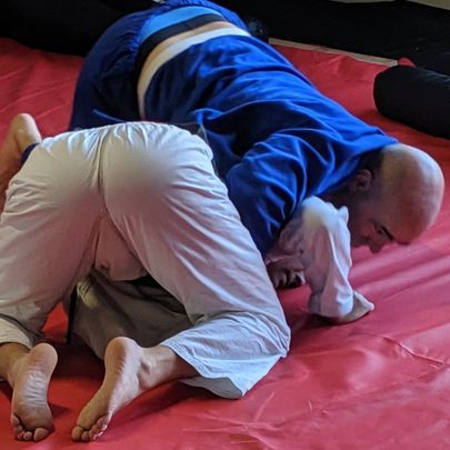 two men are wrestling on a red mat .
