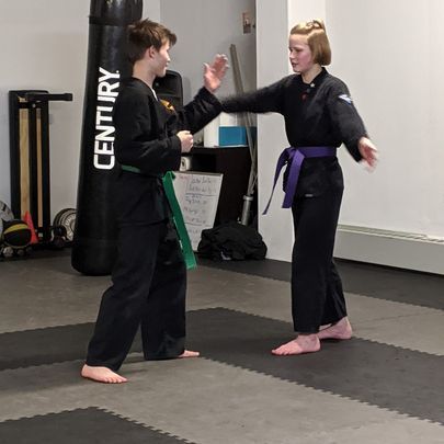 a boy and a girl are practicing martial arts in a gym .