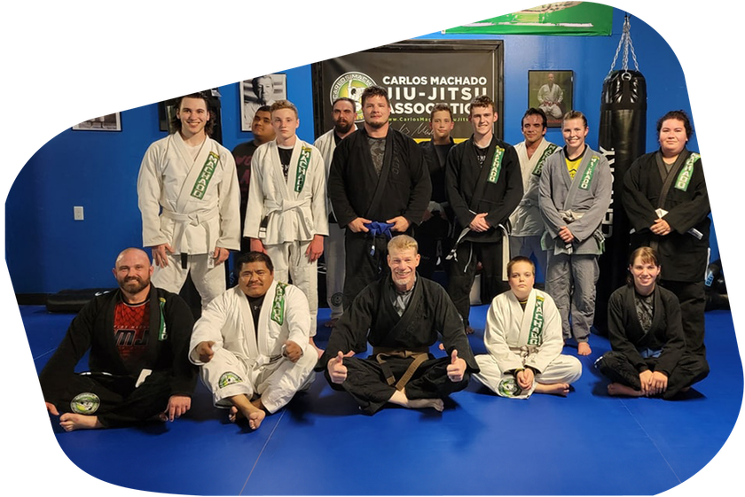 a group of people posing for a picture in front of a sign that says carlos machado jiu-jitsu association