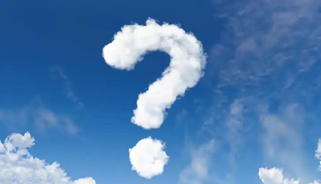White cloud formation in the shape of a question mark against a bright blue sky with wispy clouds.