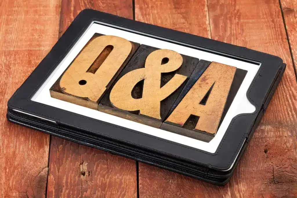 Q&A letters in wood type on a black tablet, resting on a wooden surface.