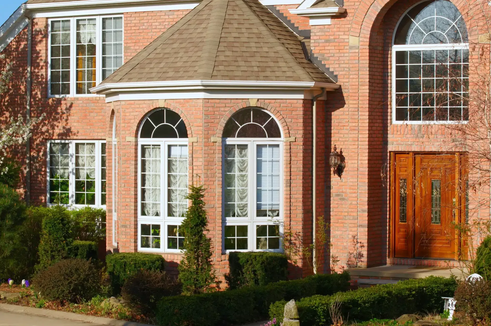 Red brick home with arched windows and a wooden front door.