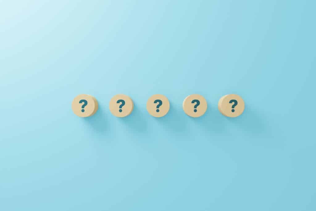 Five small, circular, tan-colored objects with question marks on a light blue background.