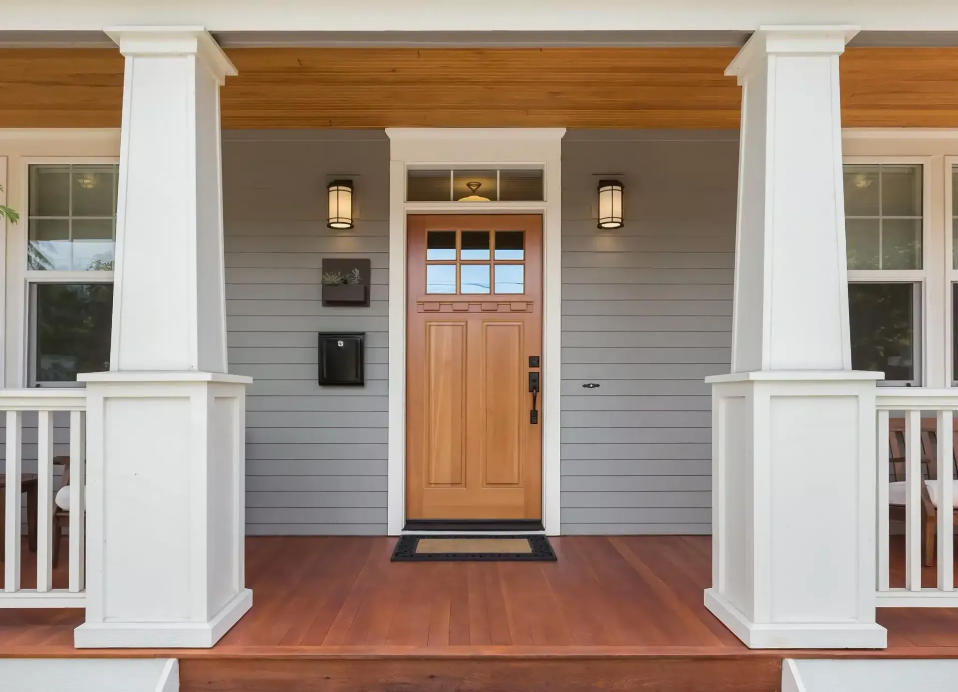 Front porch with white columns and wooden entry door.