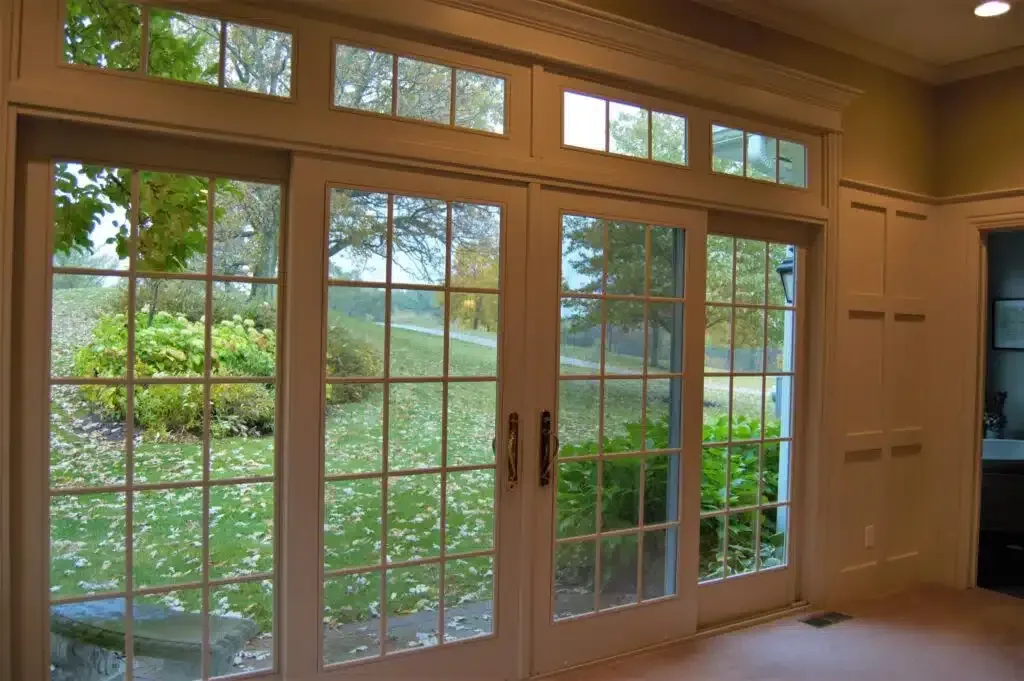 French doors with grid windows overlooking a green yard and trees.
