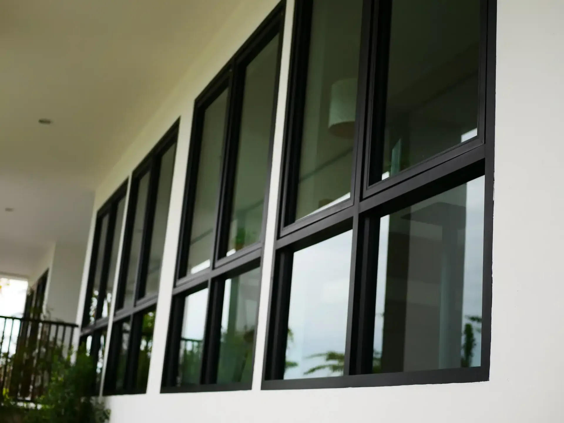 Black-framed windows on a white building exterior, reflecting the sky and interior fixtures.