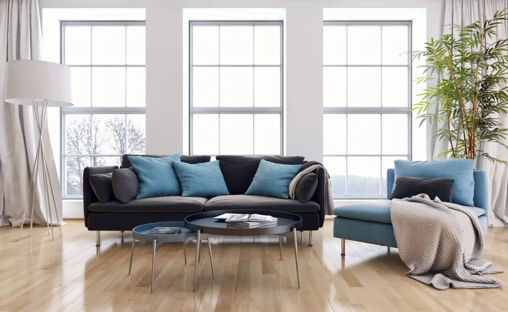 Living room with large windows, dark sofa with blue pillows, and light blue chaise lounge.