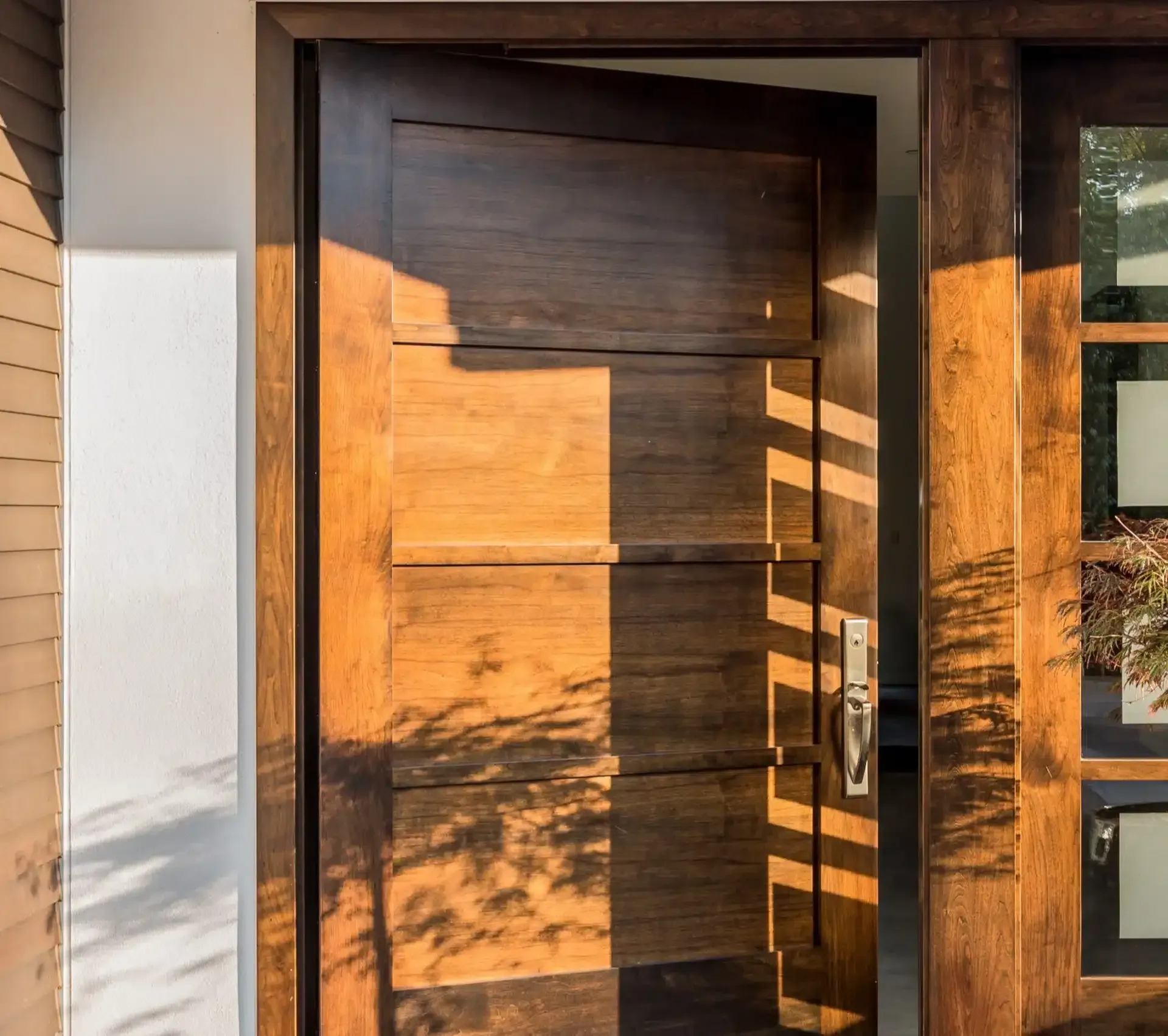 Wooden door partially open, casting shadows. Sunlight illuminates the wood's grain and the door frame.