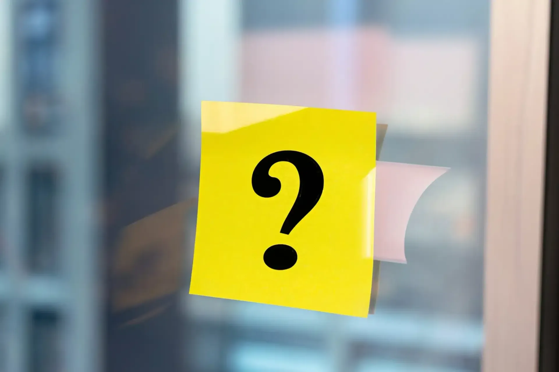 Yellow sticky note with a black question mark on a window.