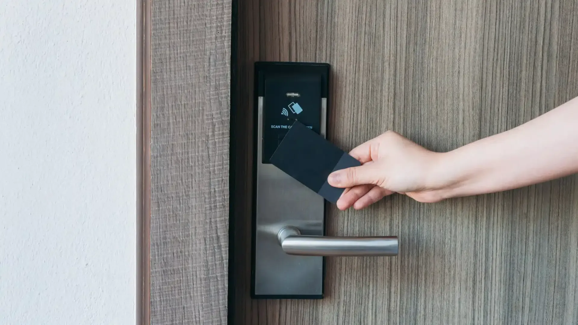 Hand holding a black key card near a hotel door lock.Photo from iStock – Credit: NewSaetiew