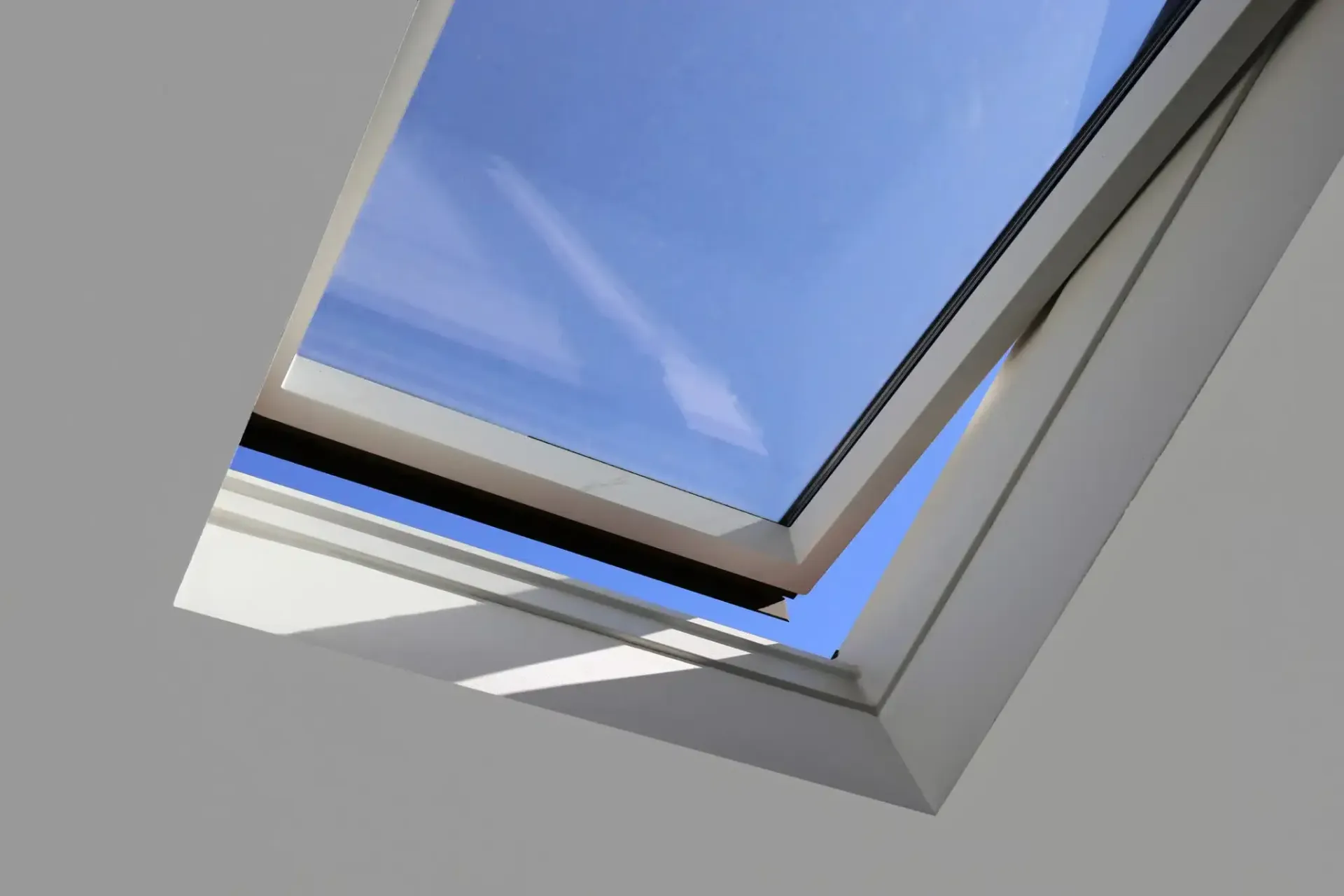 Open skylight against a bright blue sky.