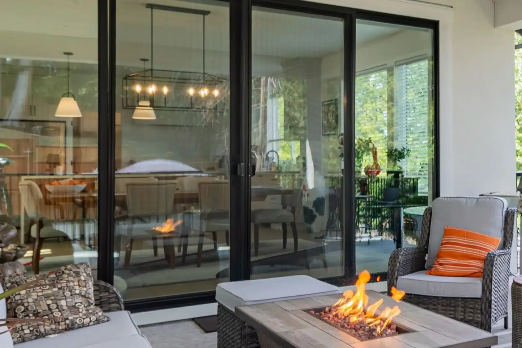 Patio with fire pit, sliding doors to dining area, outdoor furniture, and trees.