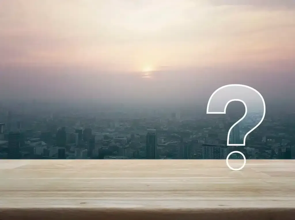 Question mark symbol over a cityscape at sunset.