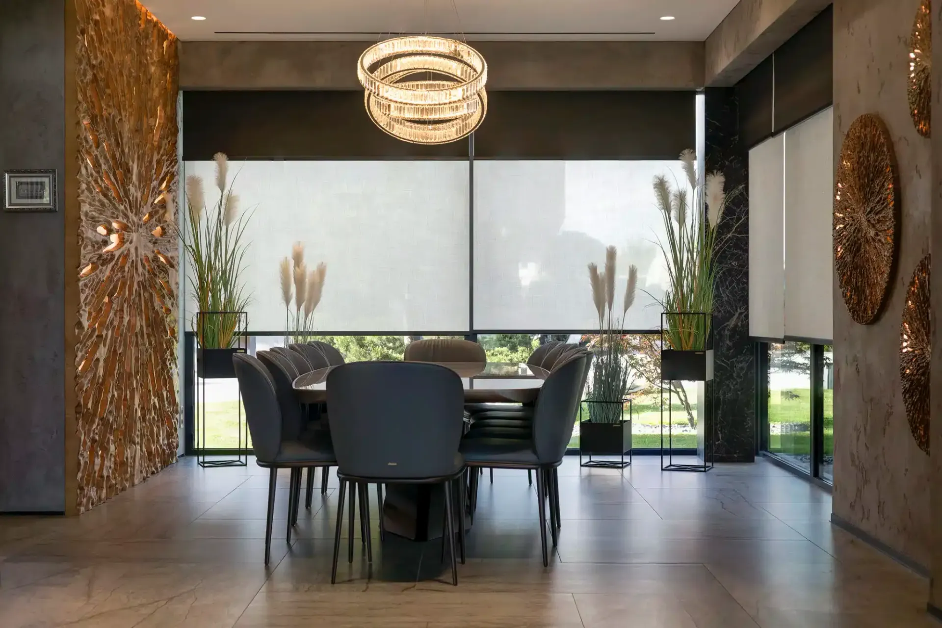 Conference room with a round table, dark chairs, decorative lighting, and a view through a window.