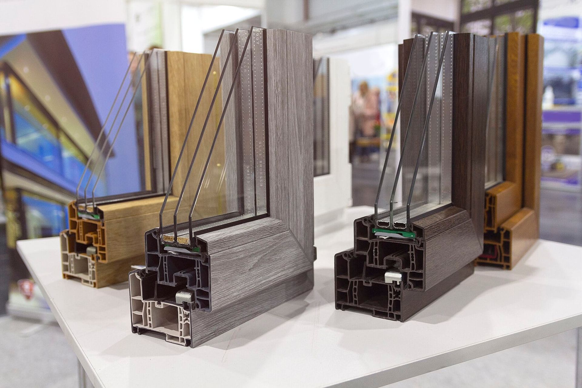 Cross-section view of four window frames in various colors, showcasing glass layers and frame construction.