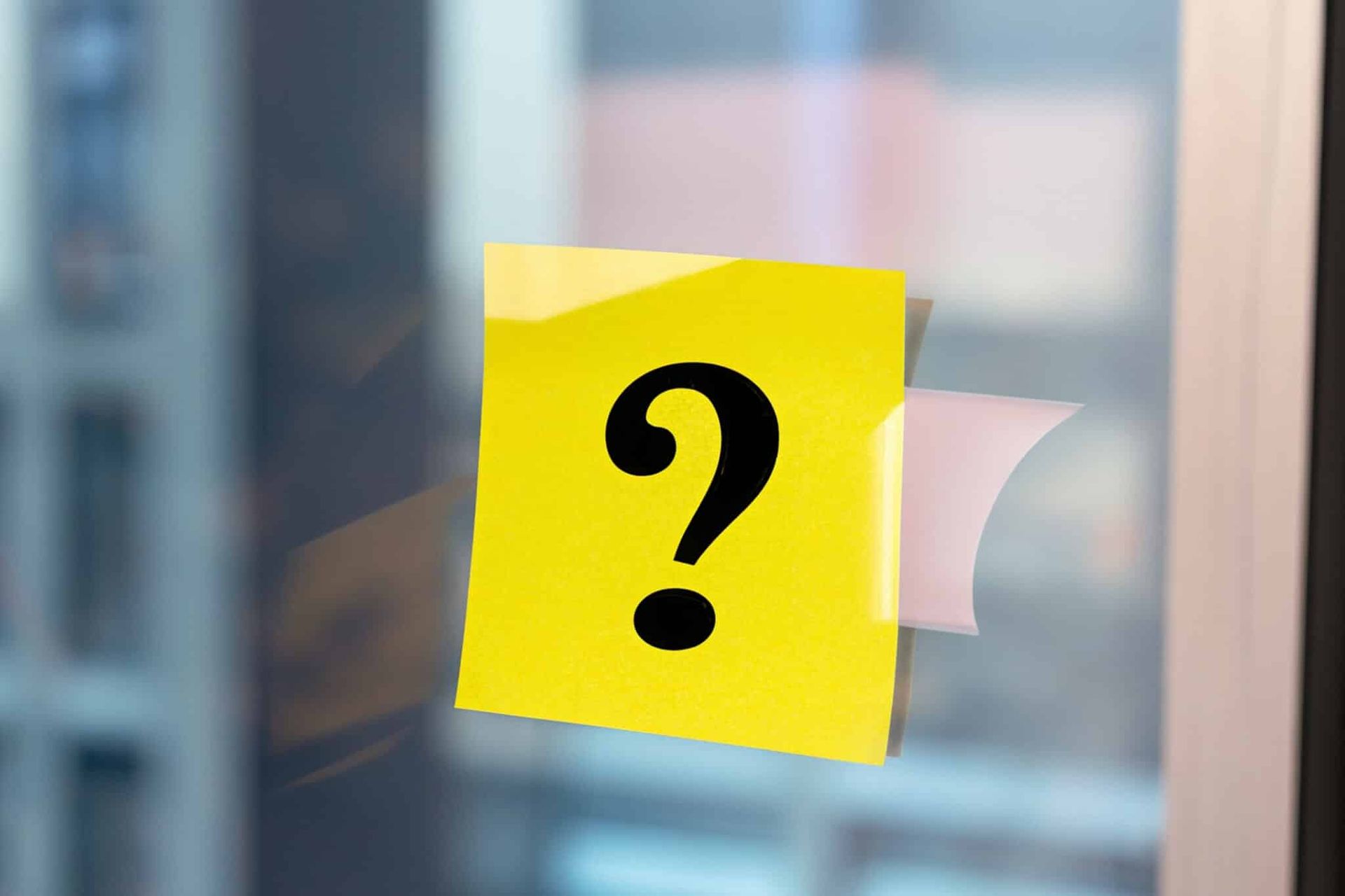 Yellow sticky note with a black question mark on a window.