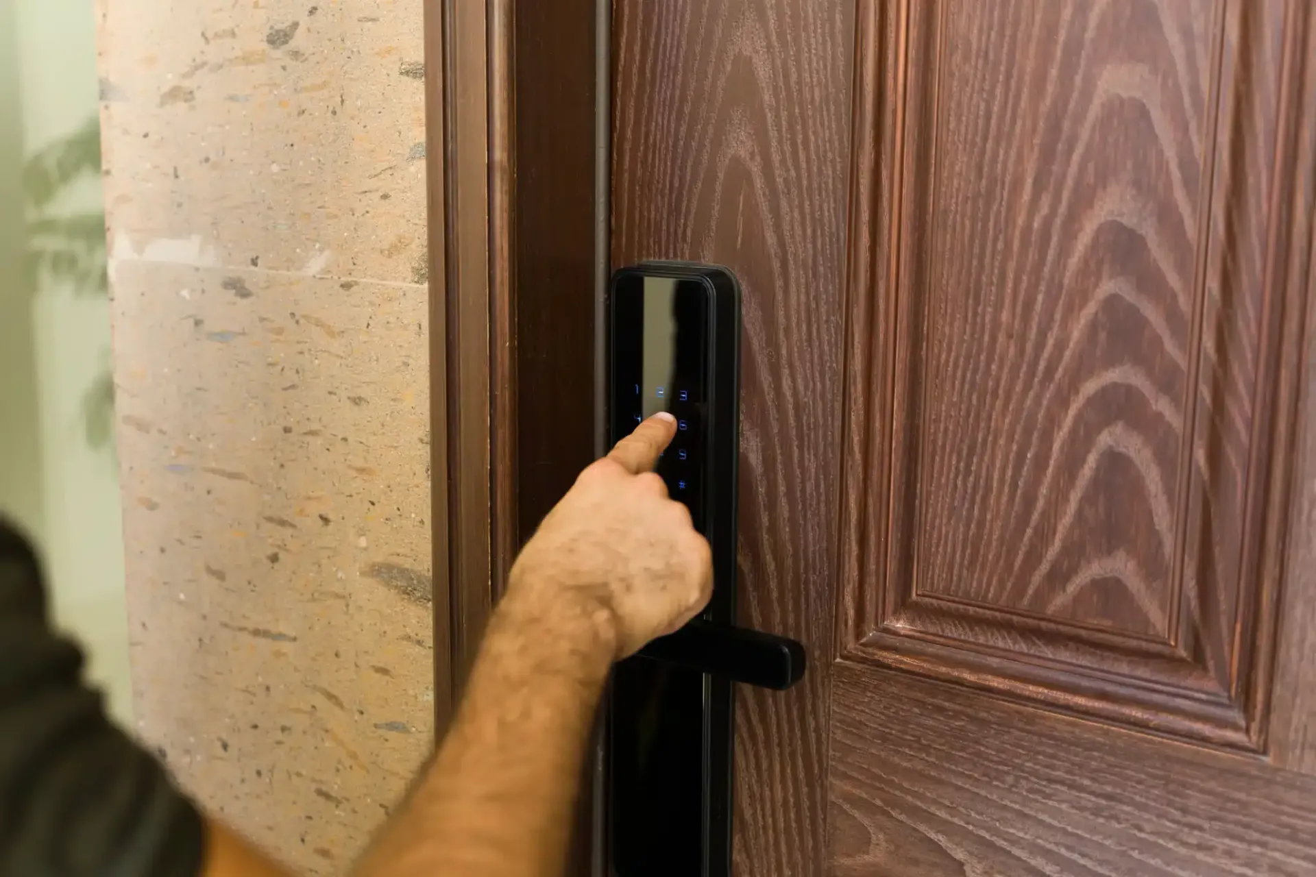 Hand using a smart lock on a wooden door, outside.
