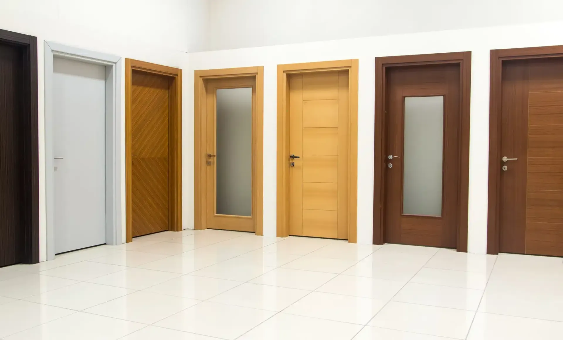 Row of wooden doors in various styles and colors, set against a white wall and glossy floor.