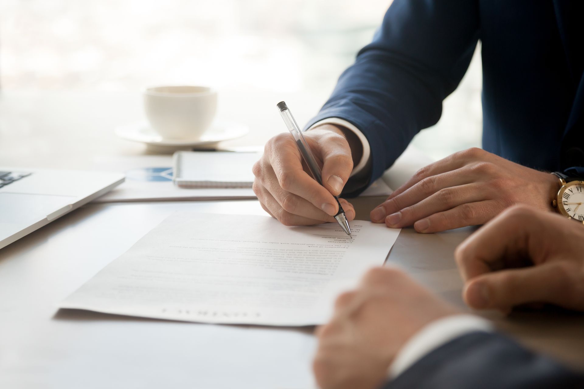 Closeup of two men’s hands signing a business contract.