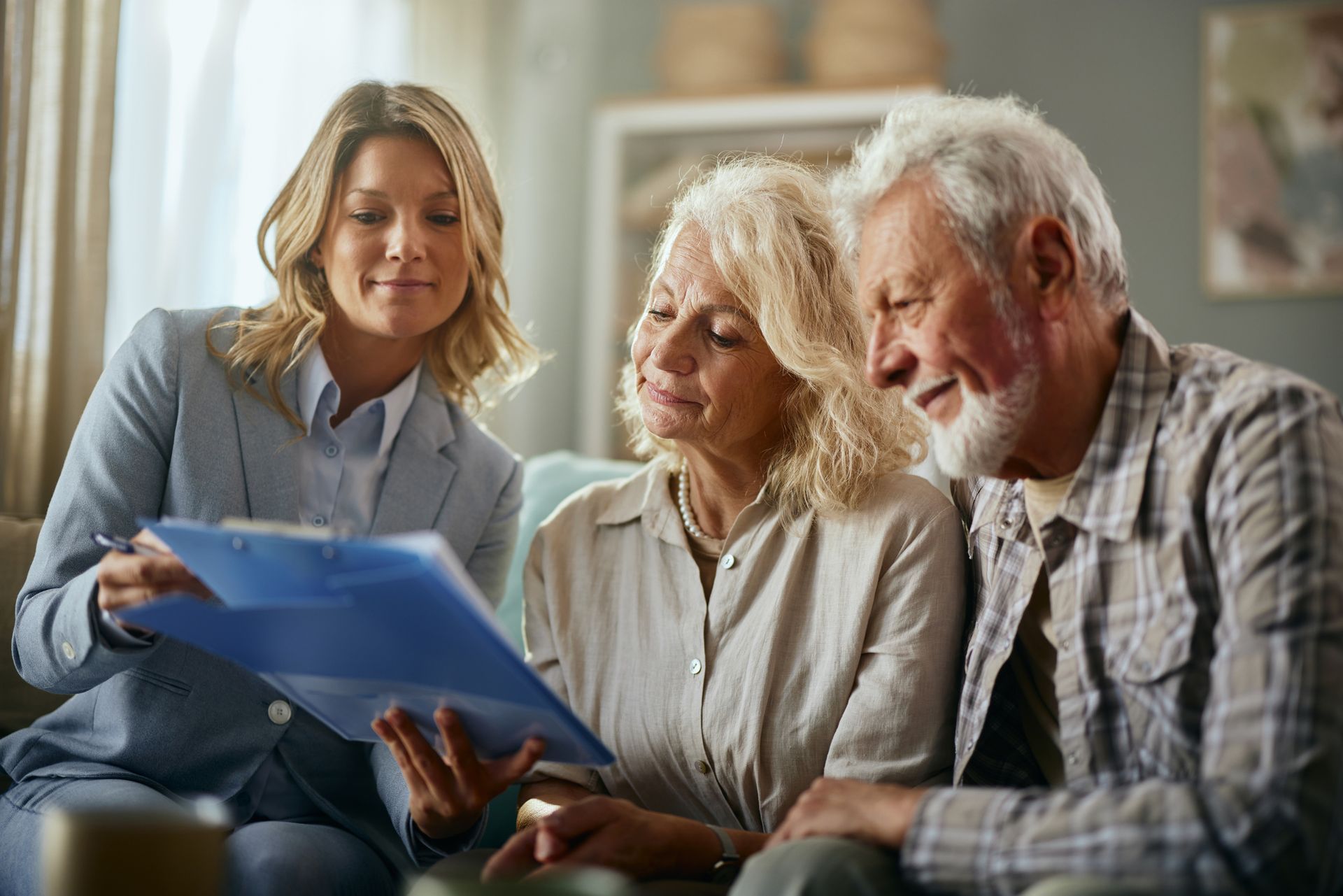 Person showing documents to two people seated on a couch in a home setting.