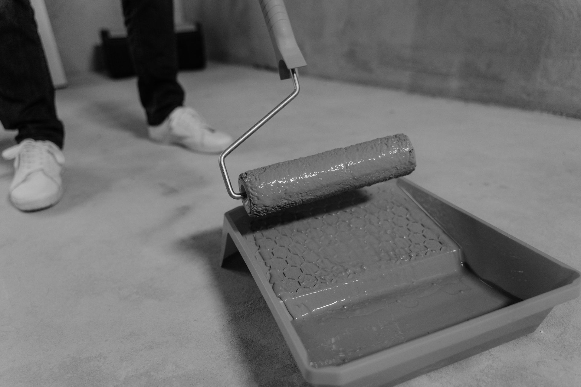 A person is painting a concrete floor with a paint roller.