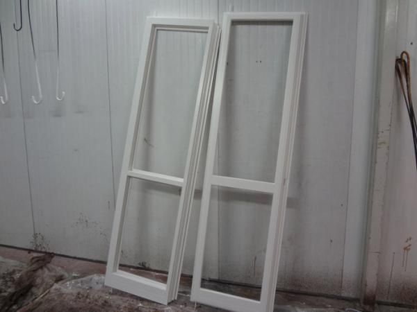 Due cornici bianche di finestre appoggiate a un muro bianco.