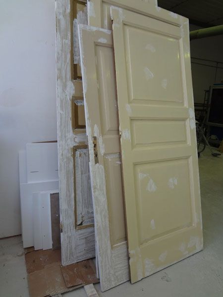 Porte interne beige appoggiate a un muro, alcune con tocchi di stucco bianco.