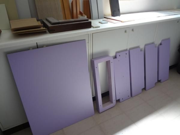 Parti di un mobile viola e pannelli rettangolari su un mobile bianco.