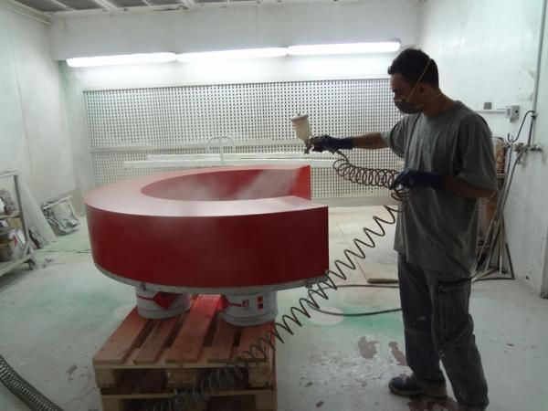 Un uomo dipinge con lo spray una grande lettera 